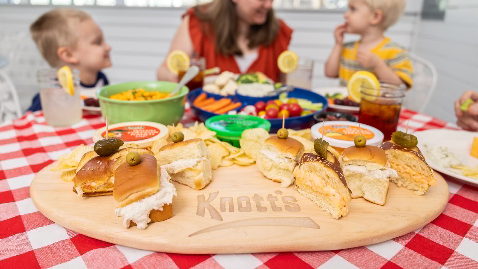a mom sitting with her two young kids as they eat Knott's in sandwich and dip form. with sweet tea and lemon slices