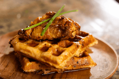 chicken and jalapeno pimiento cheese waffles stacked on a wooden plate