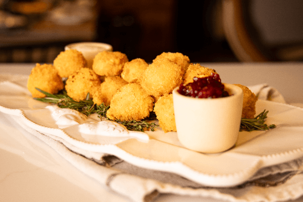 knott yo grandmas fried cheese balls on a white plate with a cup of dipping sauce