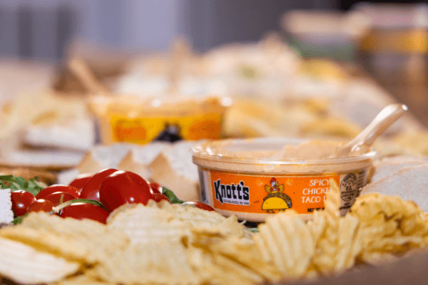 spicy chicken taco dip on a table of crackers next to cherry tomatoes